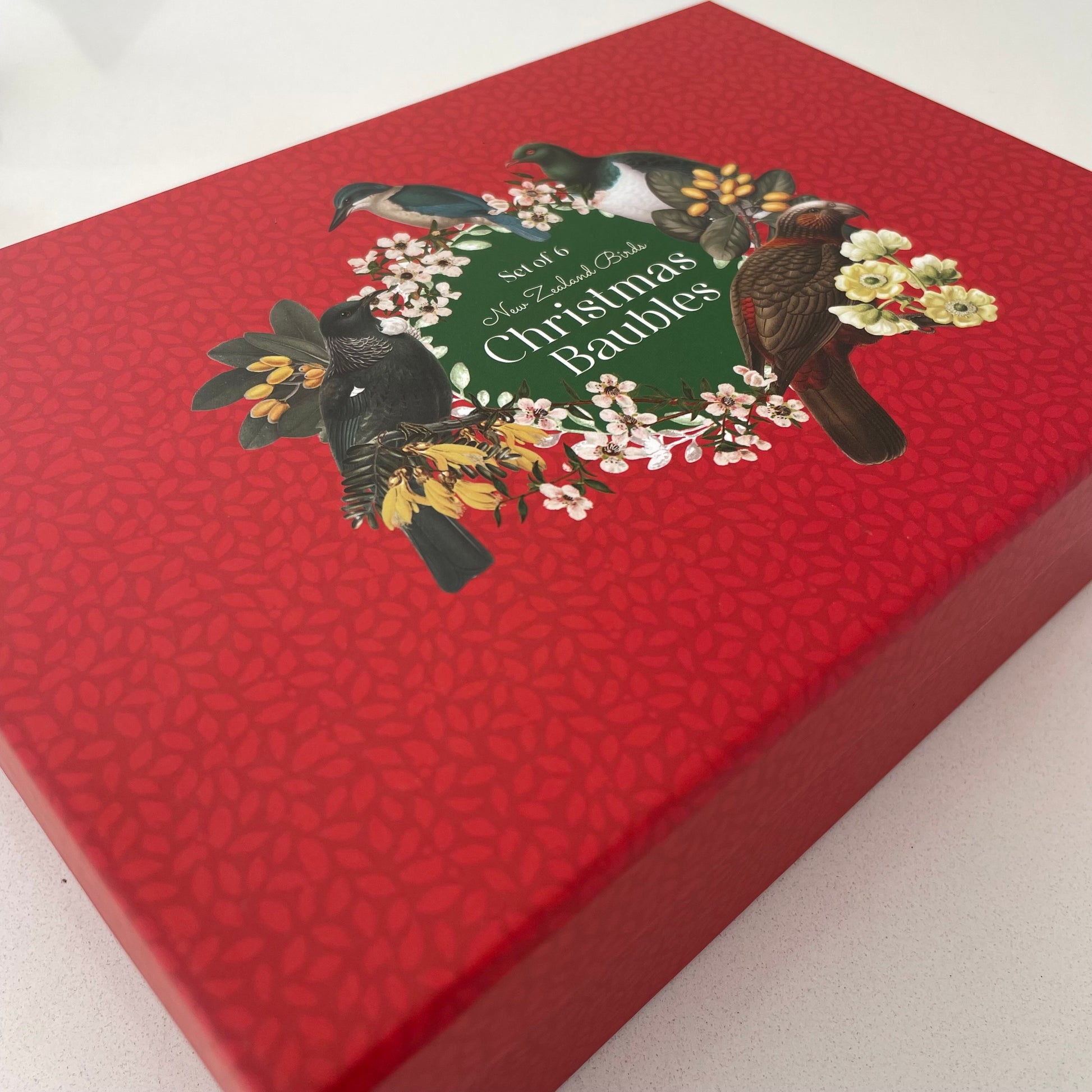 Red gift box with a NZ bird & flora print on top. Contains Christmas baubles.