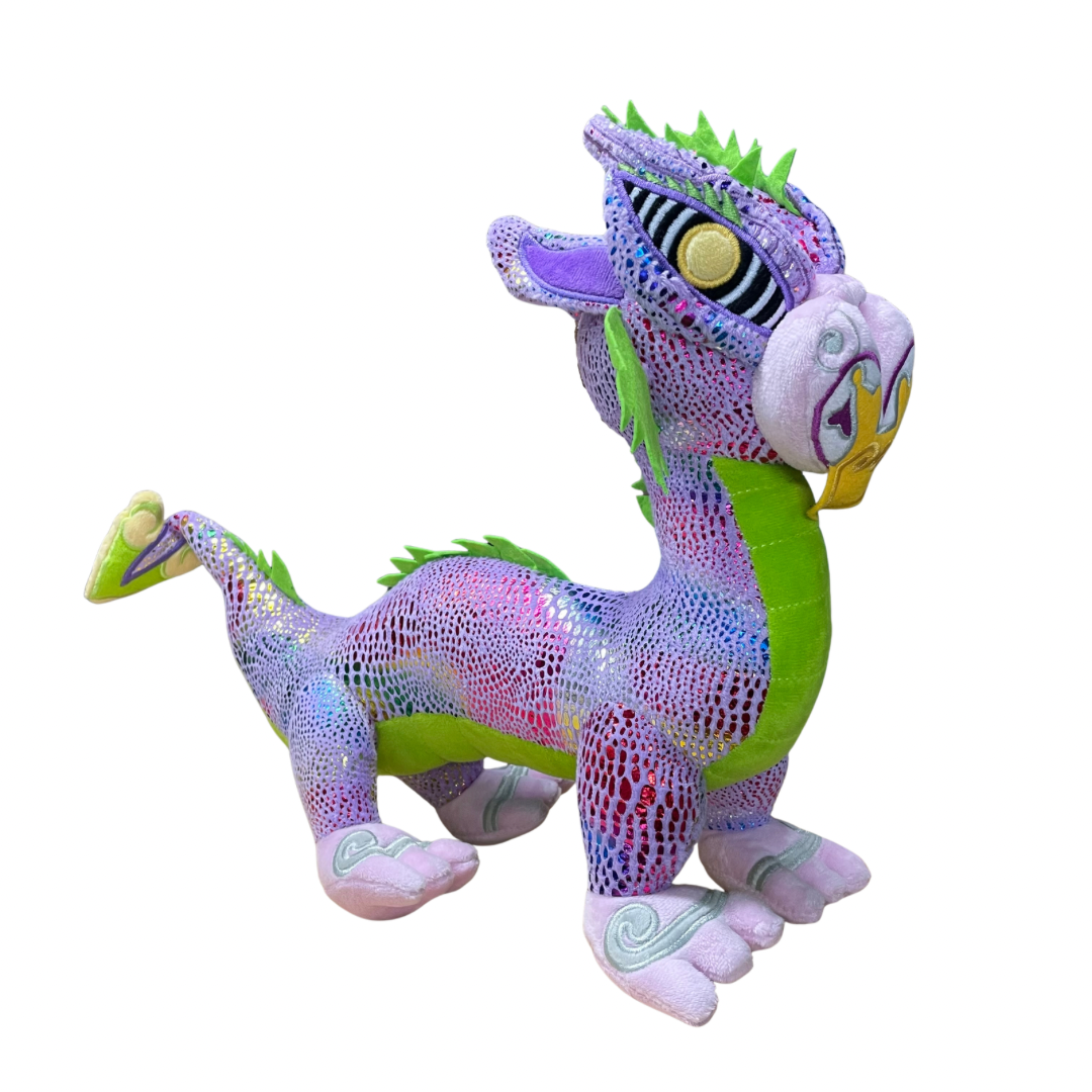 Plush toy Taniwha with purple and green base and shimmery scales in rainbow colours. Embroidered koru designs feature on the feet, tail and face.