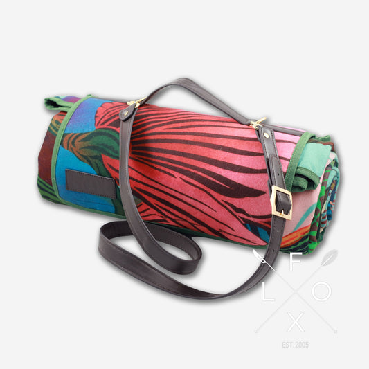 Colourful picnic blanket rolled up with straps.