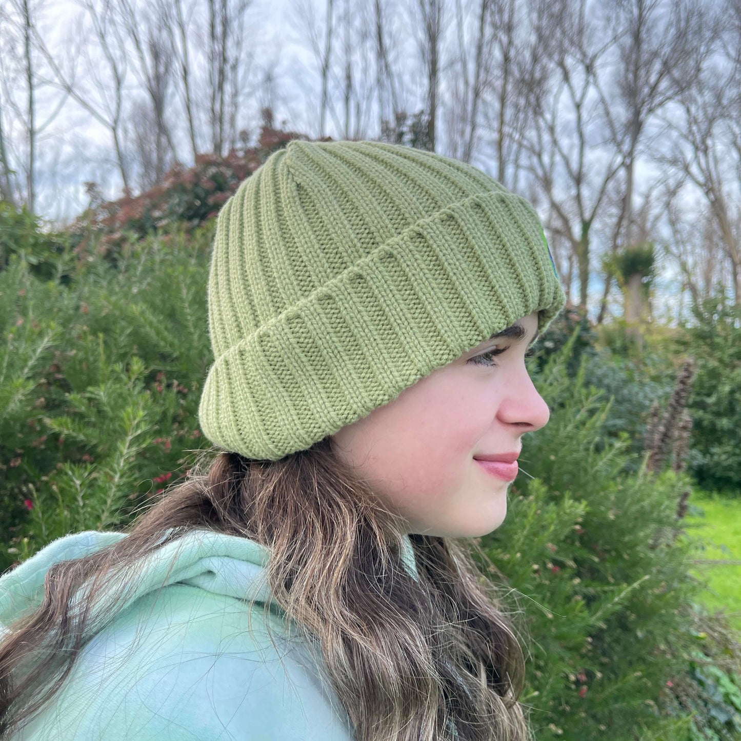 Child wearing green knit beanie, side view.