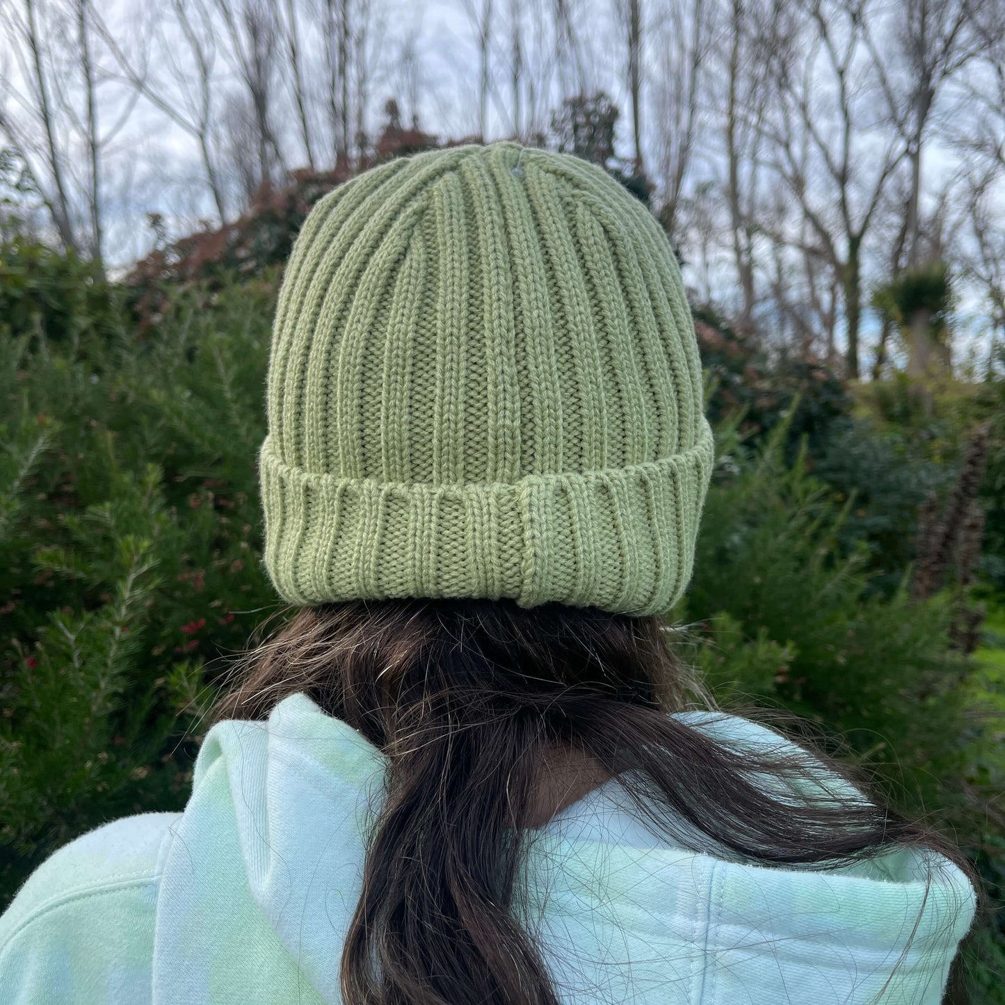 Child wearing green knit beanie rear view.