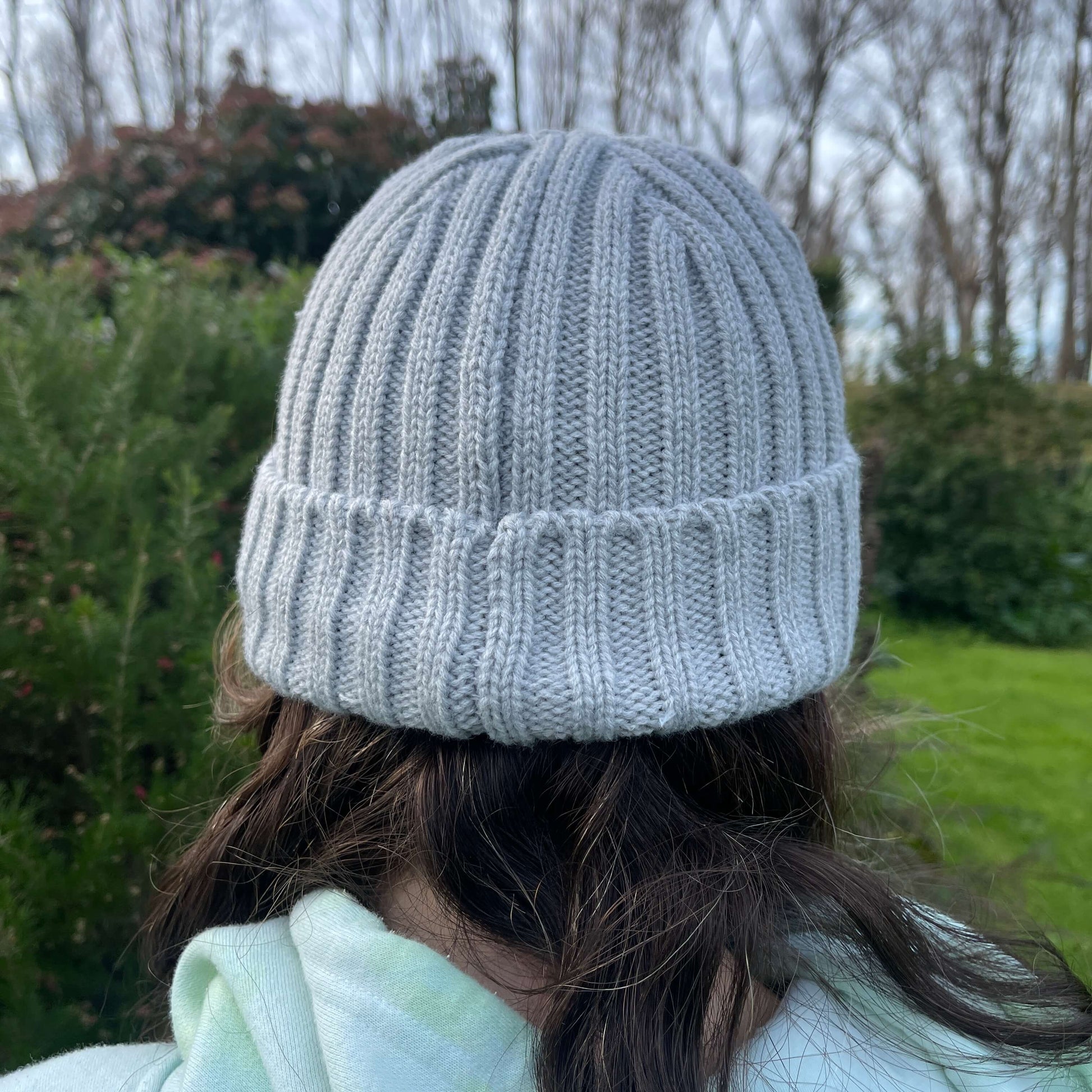 Child wearing grey knit beanie, back view.