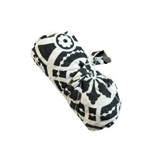 Black cotton tote bag with white floral decorative pattern rolled up and tied for storage.
