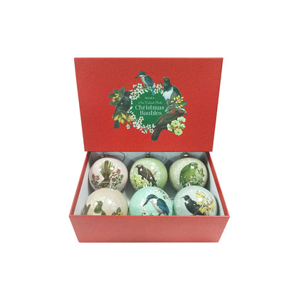 Six round Christmas baubles each in a light pastel colour. Each bauble features a native NZ bird perched on a native NZ flower. Placed in a red cardboard gift box.