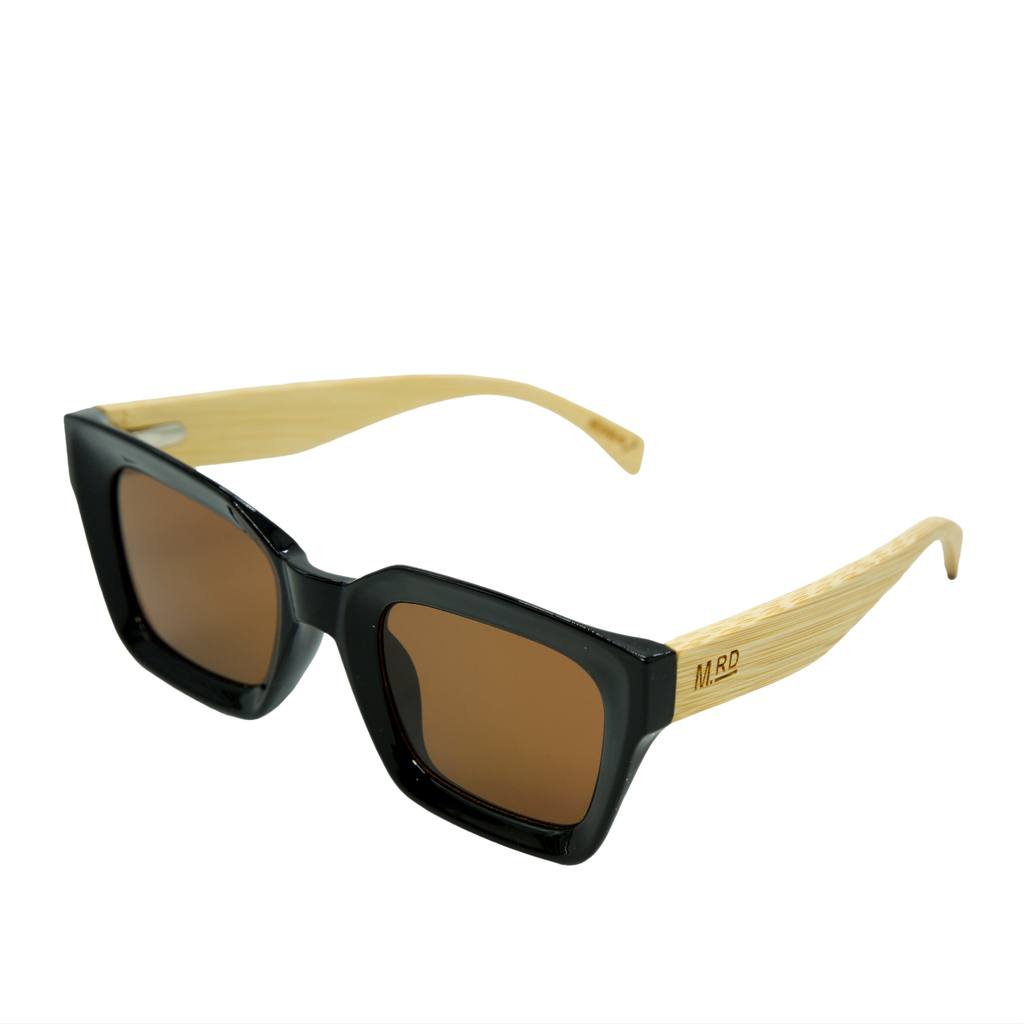 Black sunglasses with brown tinted lenses and light natural wooden arms, featuring an engraved 'MRD’ logo on the arm.