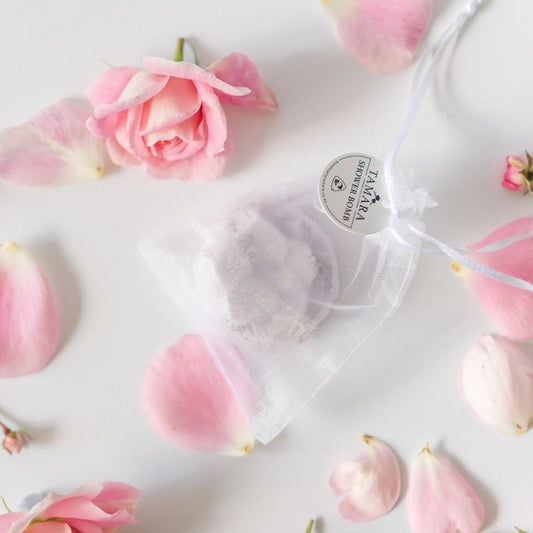 Individual shower bomb in an organza bag surrounded by rose petals.