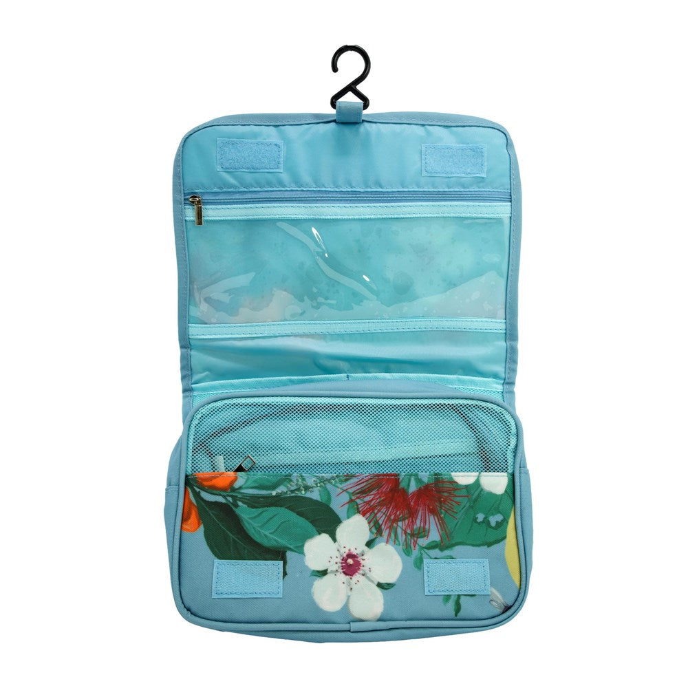 Inside of a hanging pale blue toiletry bag with New Zealand floral pattern on the bottom pocket..