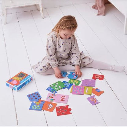 Child playing on the floor with a Peppa Pig counting puzzle.
