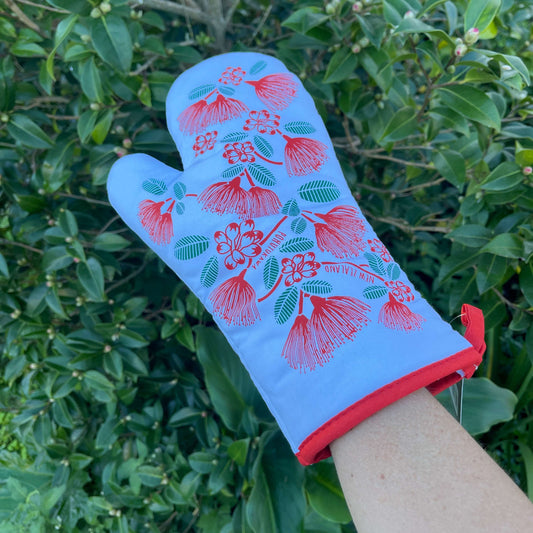 White oven mitt with red pohutukawa flowers and green leaves.