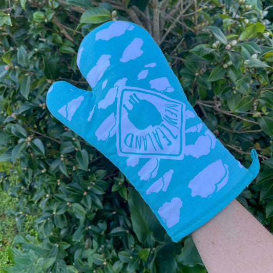 Blue oven mitt with white clouds and a silhouette road sign featuring a sheep and the words New Zealand.