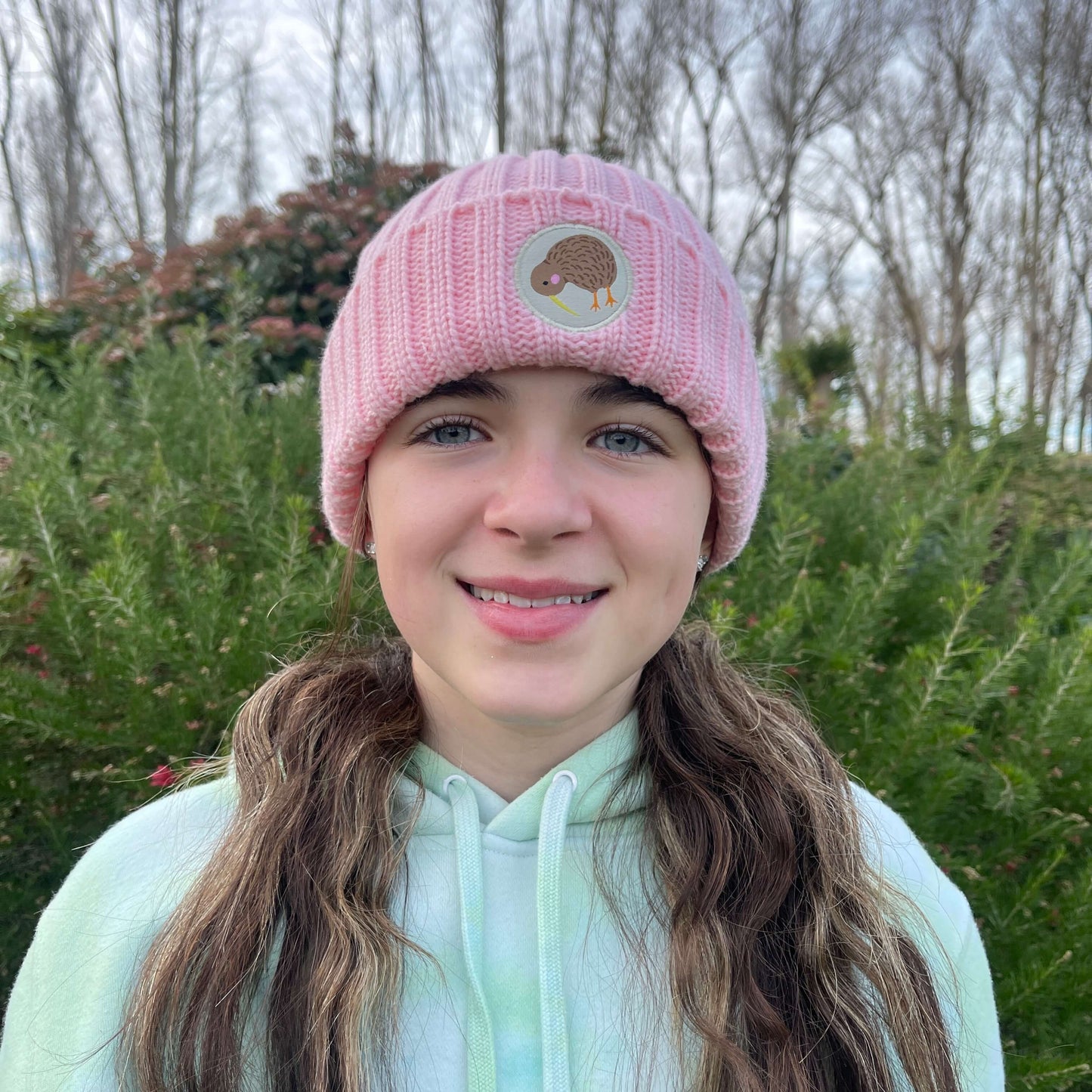 Kids pink knit beanie with Kiwi emblem on the front.