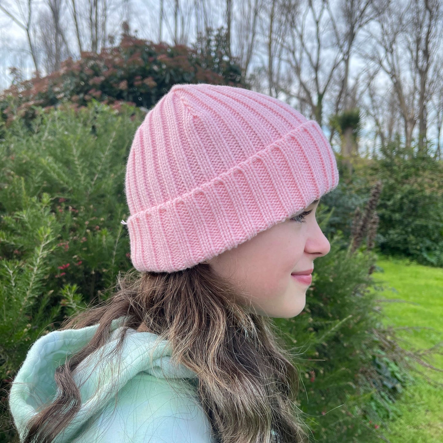 Child wearing pink knit beanie, side view.