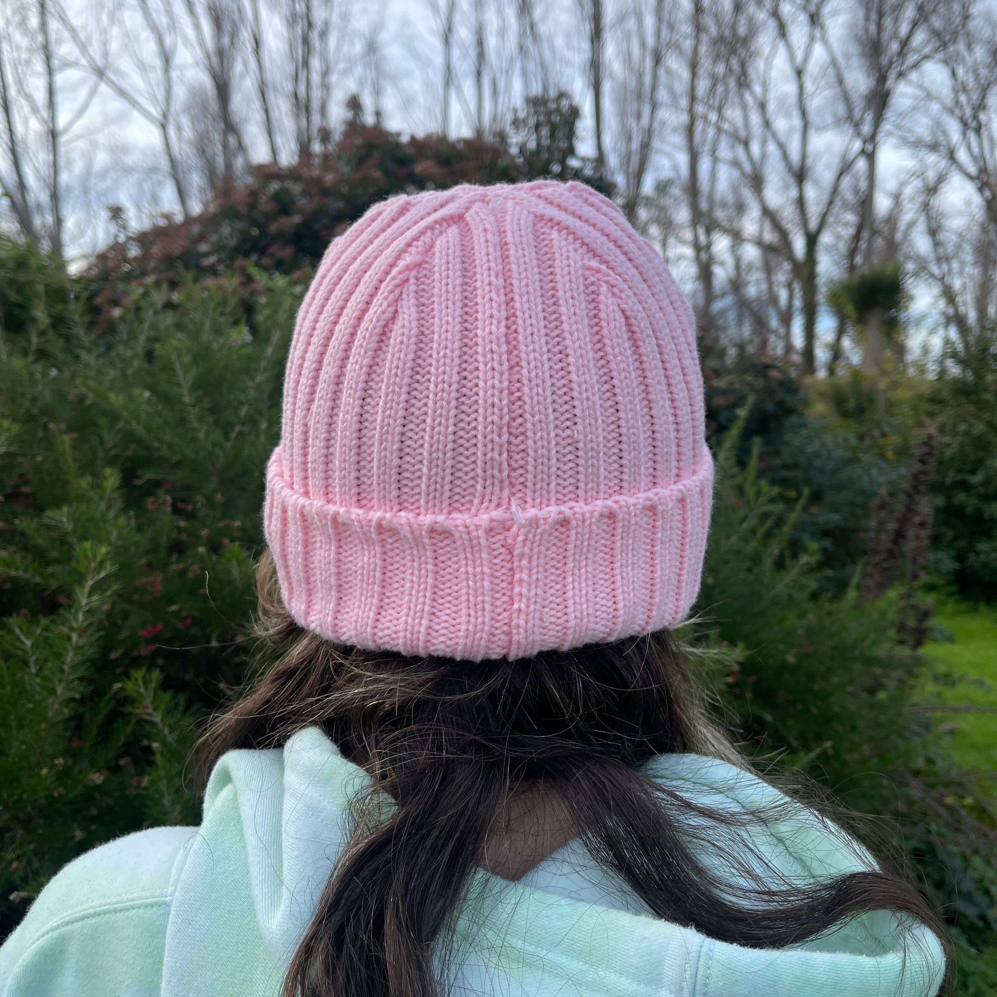Child wearing pink knit beanie, back view.