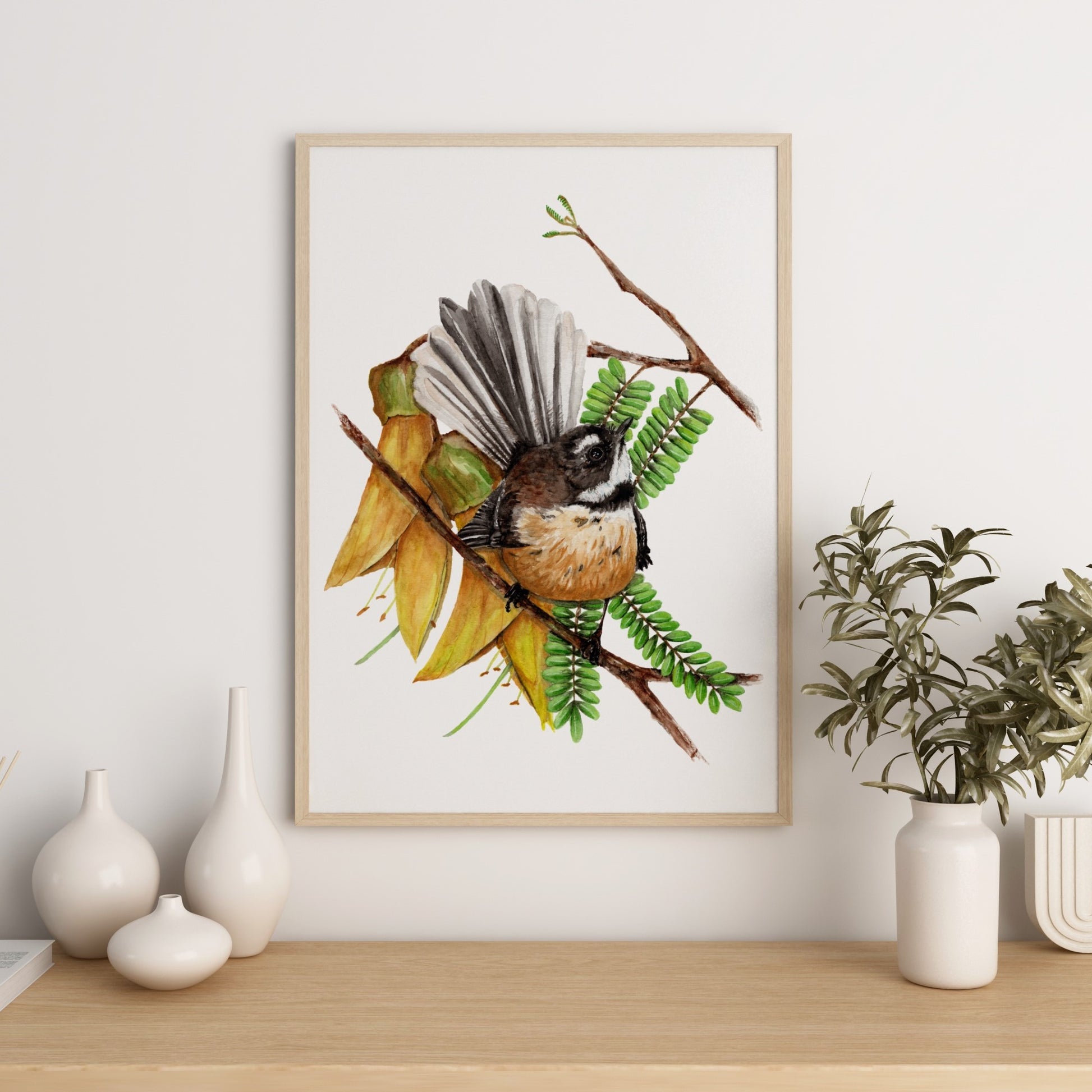 Watercolour artwork featuring a fantail bird perched amongst Kowhai flowers.