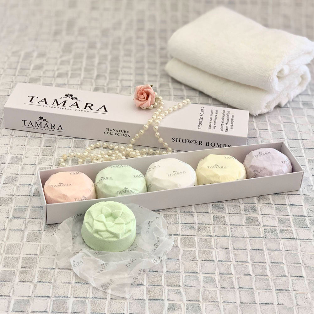 Collection of shower bombs beautifully presented in a box on a white tile background.