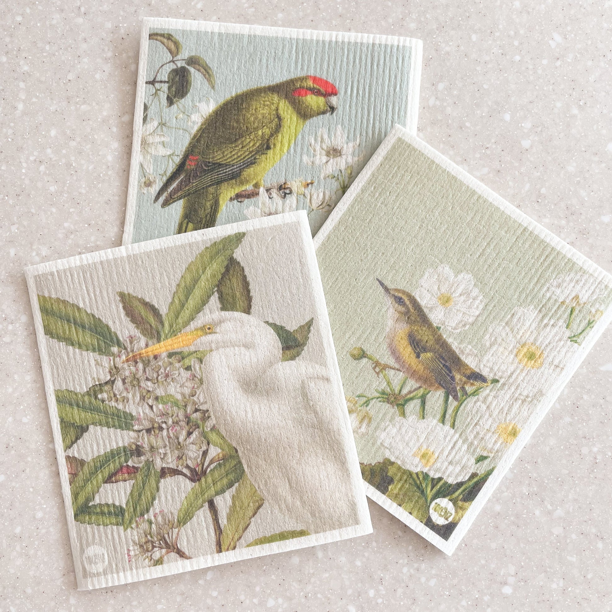 Set of 3 Swedish dishcloths featuring native New Zealand birds and flowers; Kakariki and Puawanaga, Rifleman and Mt Cook Lily and the Kotuku and Tawari flower.