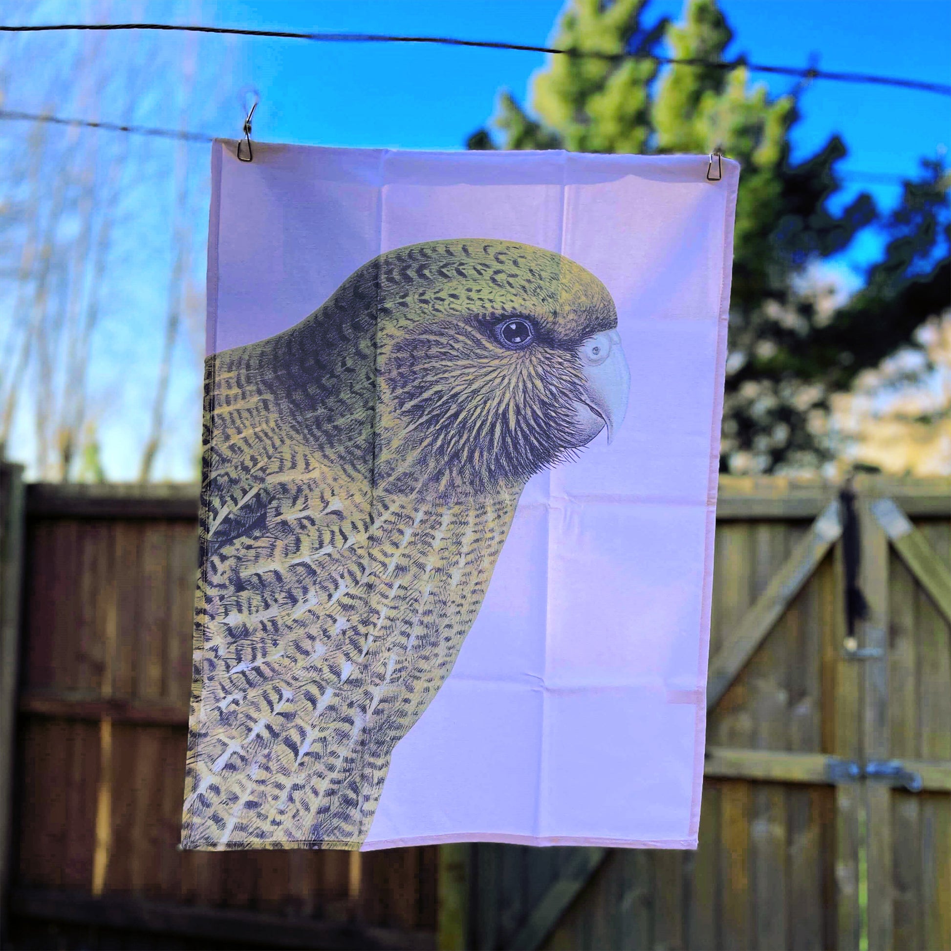 Pale pink tea towel with a Kakapo bird on it.