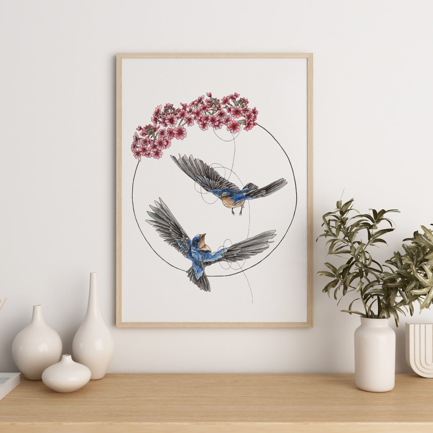 Watercolour art featuring 2 swallows flying together tethered by a string in a circle and topped with primrose flowers.