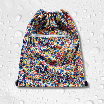 Drawstring backback style wetbag in mutlicoloured dot print and a zip pocket on the front.