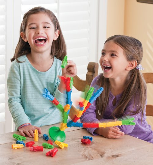 Two young girls playing with the Toppletree game at a dining table. 