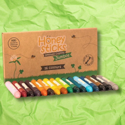 Honeysticks jumbo crayon with 16 bright multi-coloured crayons in front with a crumpled green paper background