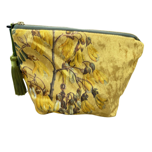 Golden velvet cosmetic bag with Kowhai flowers on it.