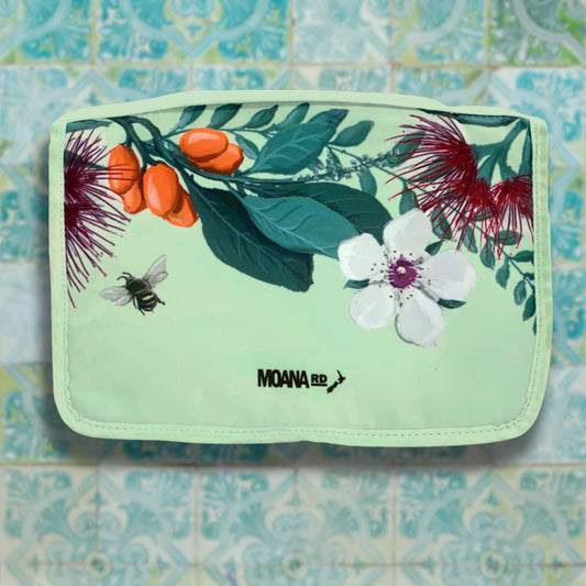 Pale green toiletry bag with New Zealand floral pattern at the top.
