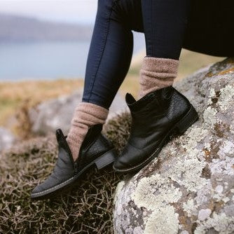 Picture of a womens feet wearing brown woolen socks and black ankle boots.