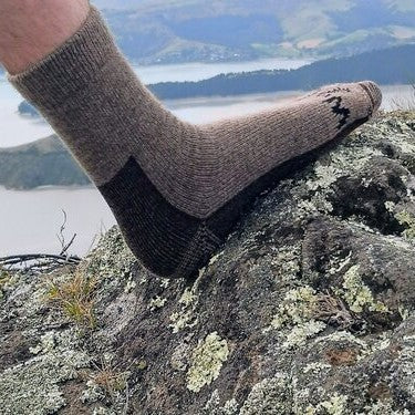 Mans foot in a brown woolen sock resting on a rock.