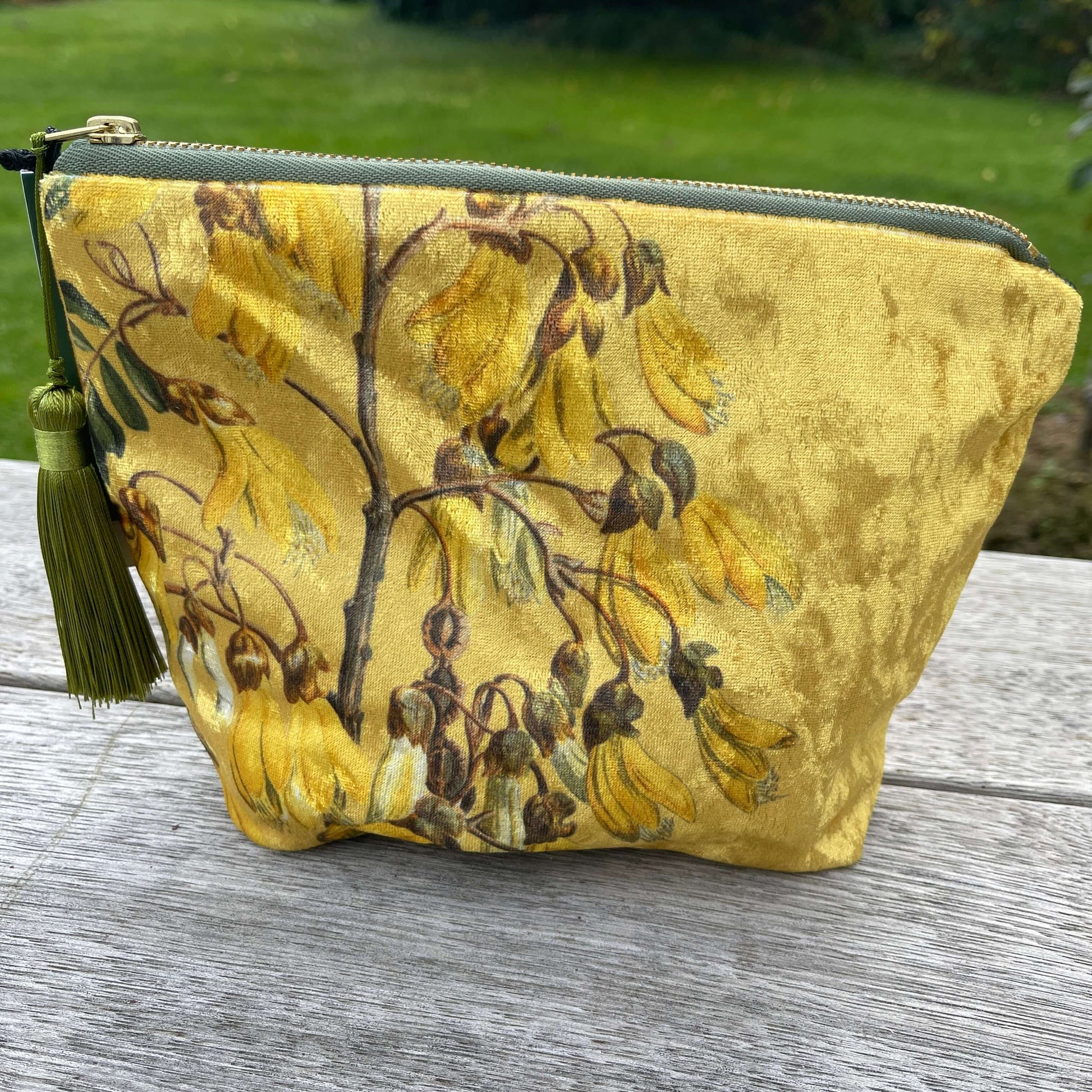 Golden velvet cosmetic bag with Kowhai flowers on it.