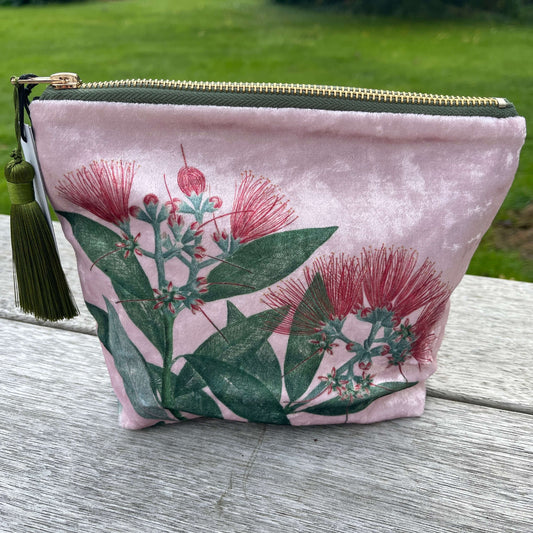 Pale pink velvet cosmetic bag with green tassel and a pohutukawa flower print.