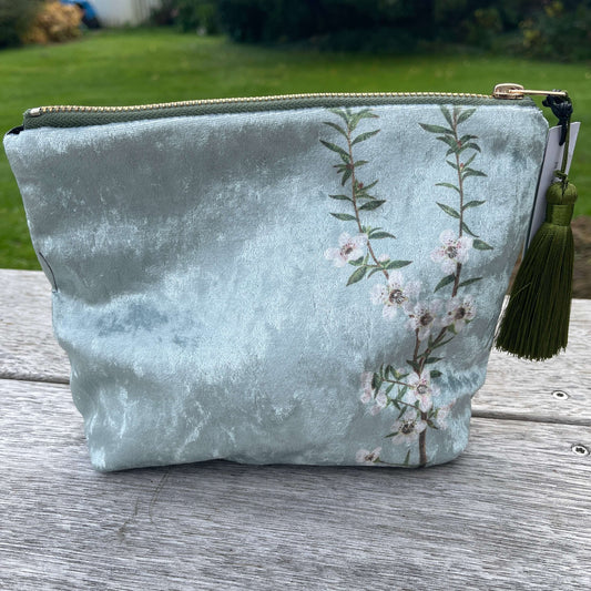 Icy blue velvet cosmetic bag with Manuka flowers and a green tassel.