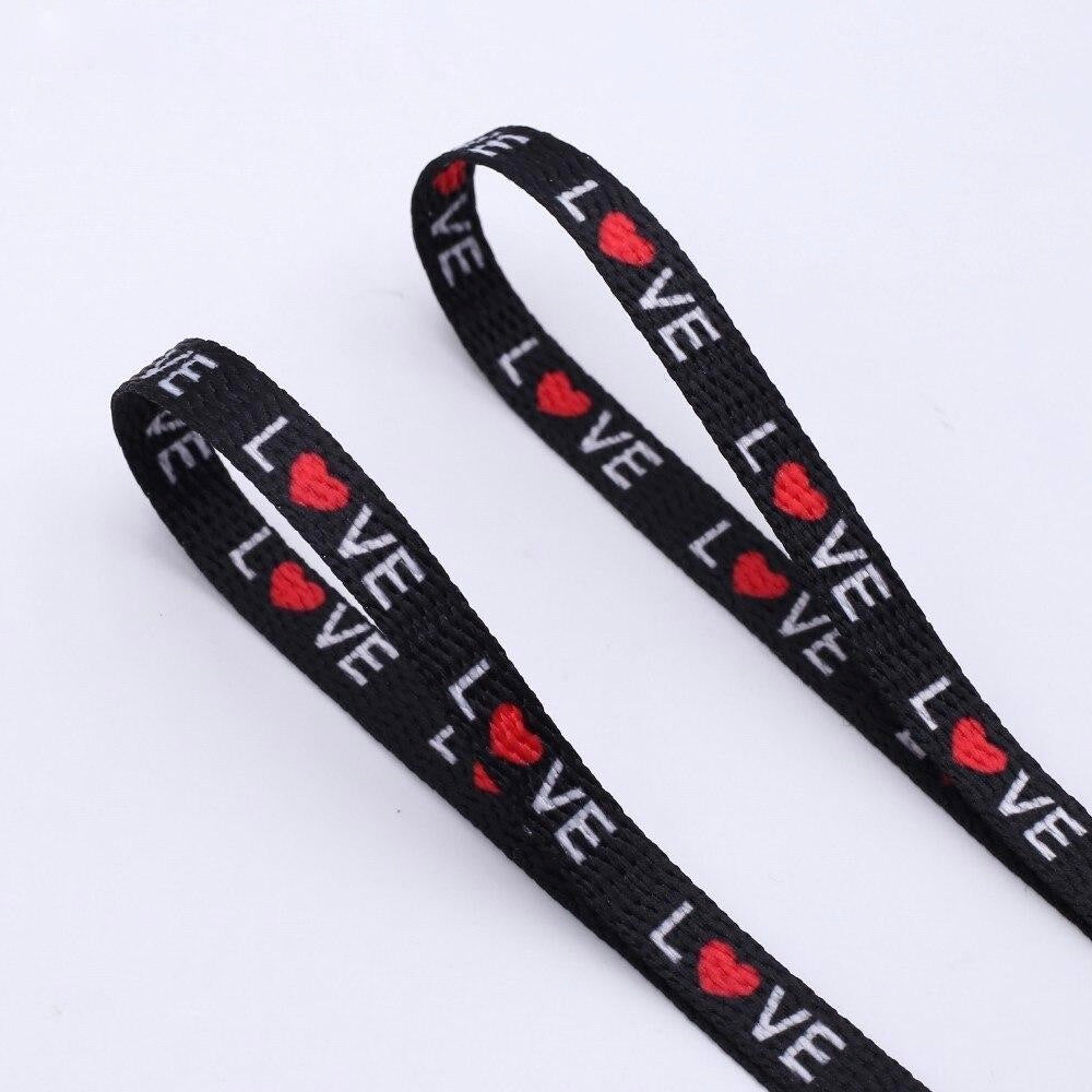 Black shoelaces with the word love printed on them and the O is a red heart.