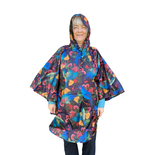 Woman wearing a rain poncho with birds and flower print on a deep aubergine purple background.