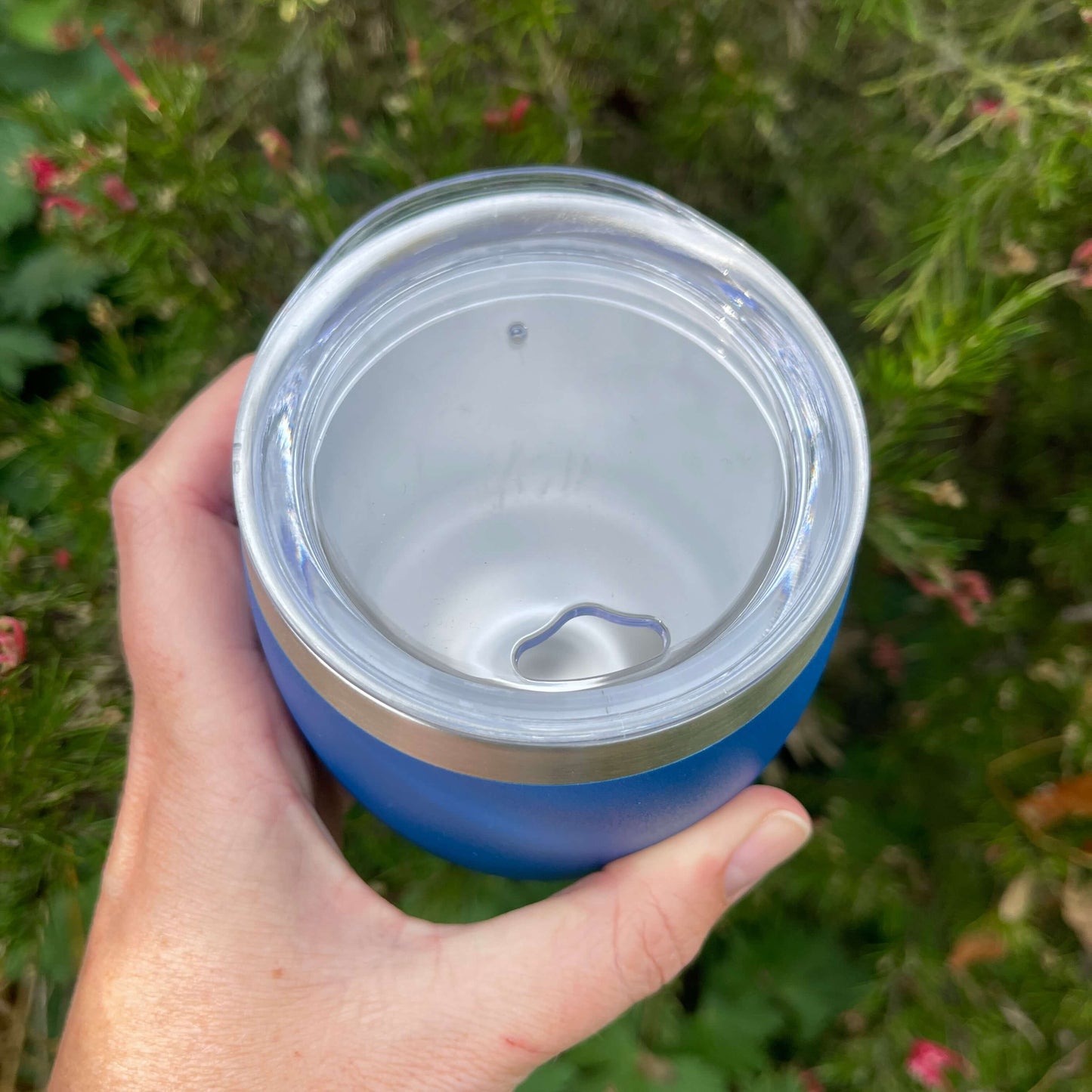  Birds eye view of a stainless coffee mug featuring the clear plastic sipper top.