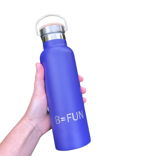 Womens hand holding a dark blue stainless drink bottle with a bamboo cap and the words B=FUN engraved on it.