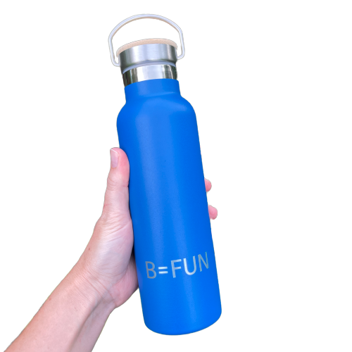 Womens hand holding a bright blue stainless drink bottle with a bamboo cap and the words B=FUN engraved on it.