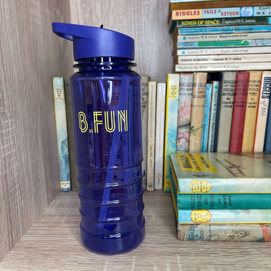 Bright purple plastic sports water bottle with B=Fun printed on it sitting on a book shelf next to vintage books.