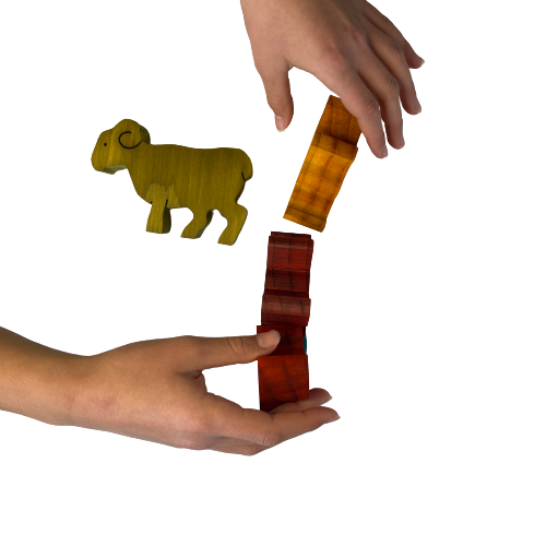 Hands playing with wooden balancing sheep.