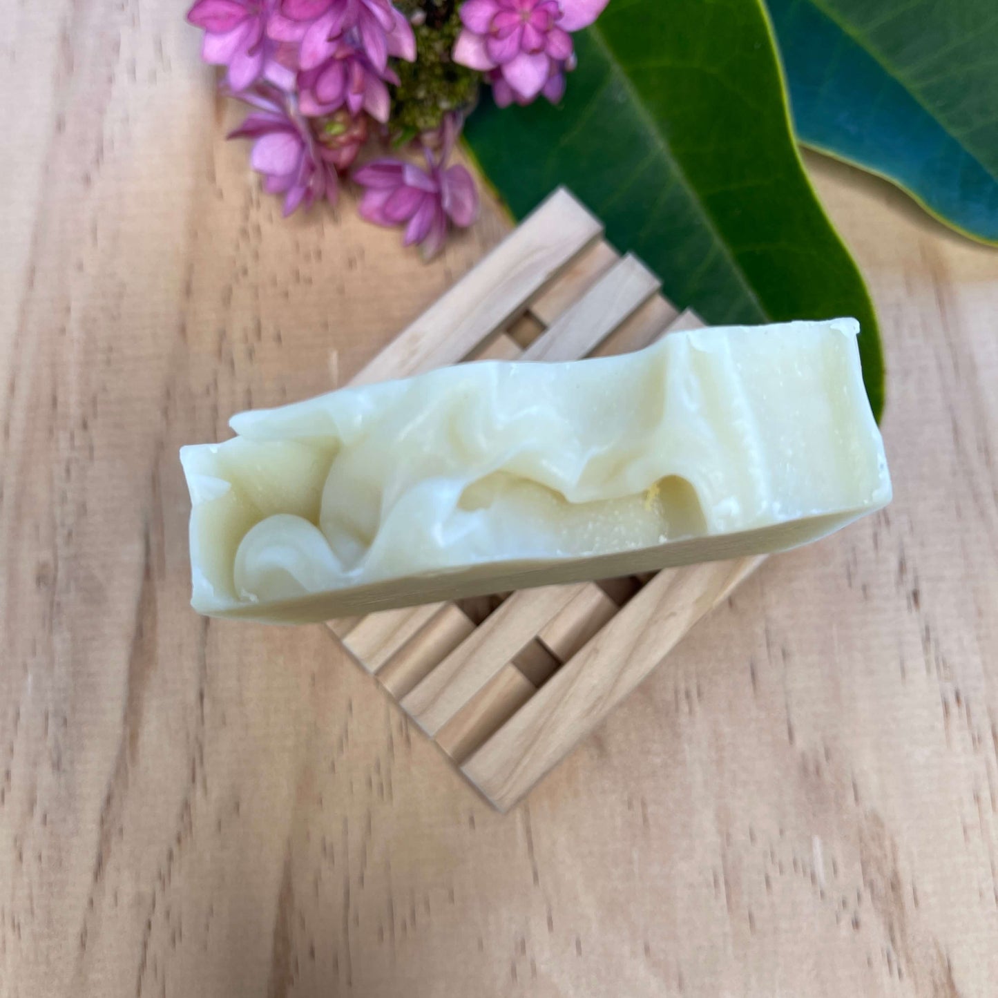 Lavender body soap on a wooden soap dish.