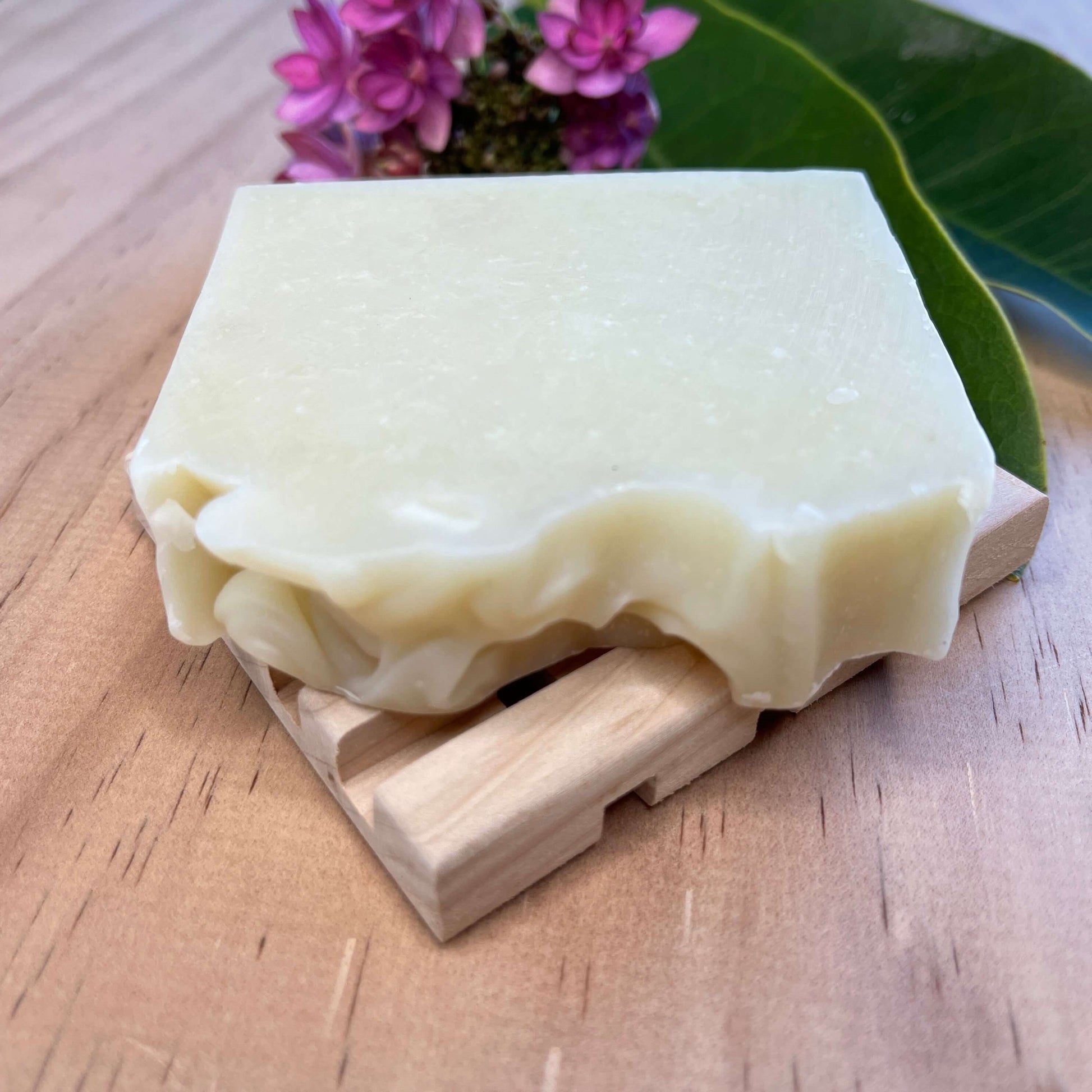Lavender body soap on a wooden soap dish.