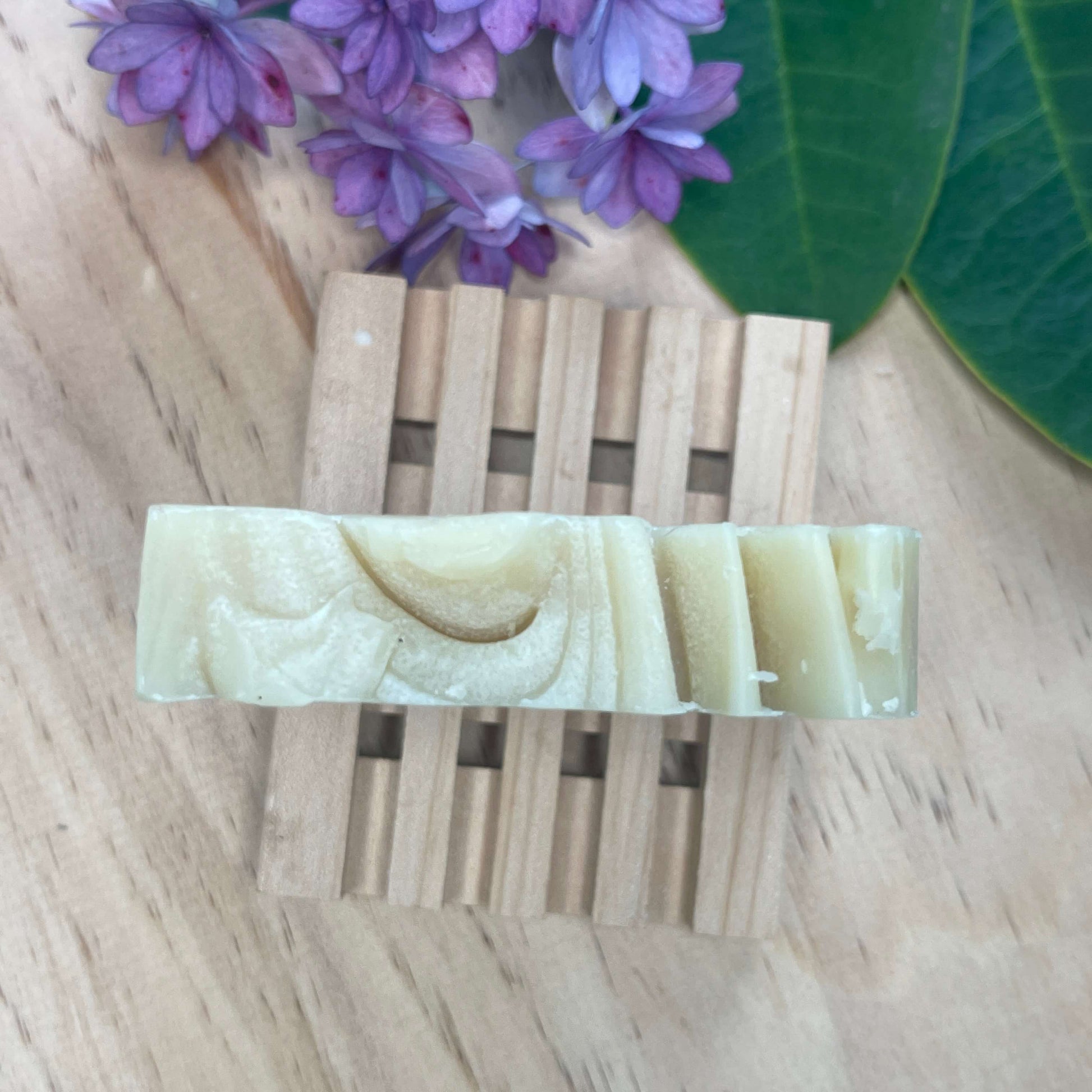 Natural shampoo bar on a wooden soap rack.