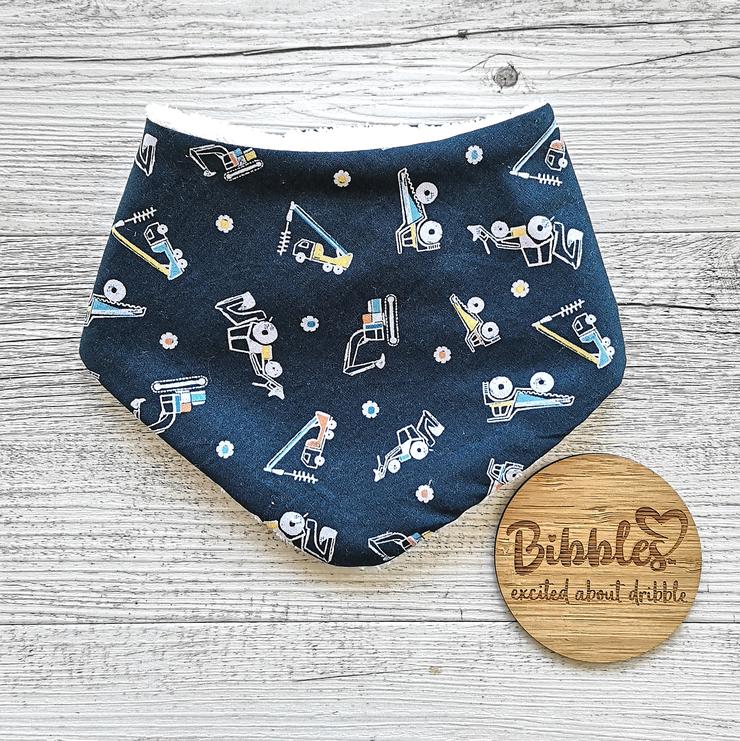 Baby dribble bib in dark teal fabric with construction vehicle print.