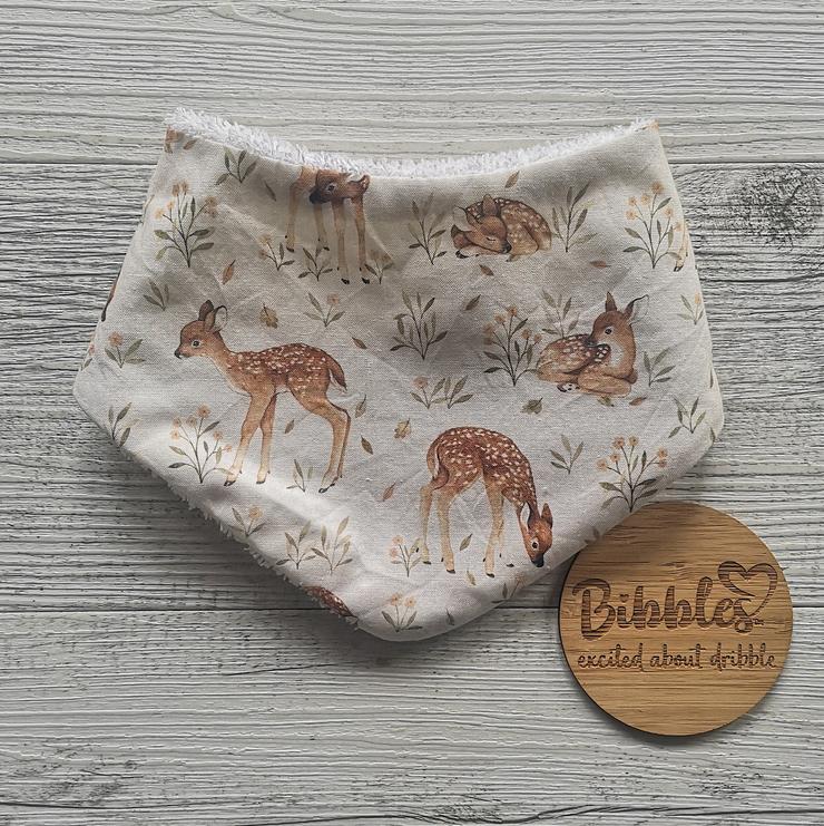 Baby dribble bib in cream fabric with watercolour deers and flowers.