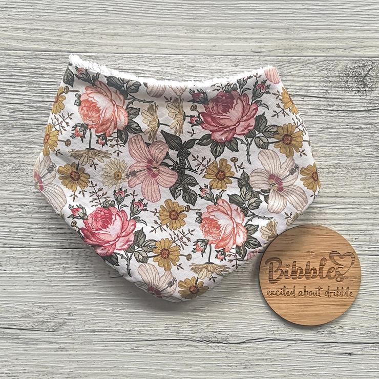 Baby dribble bib with white fabric background and a vintage floral print in mustards, dusky rose, cream and green colours.
