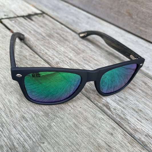 Sunglasses with dark wooden arms, black frames and green reflective lenses.