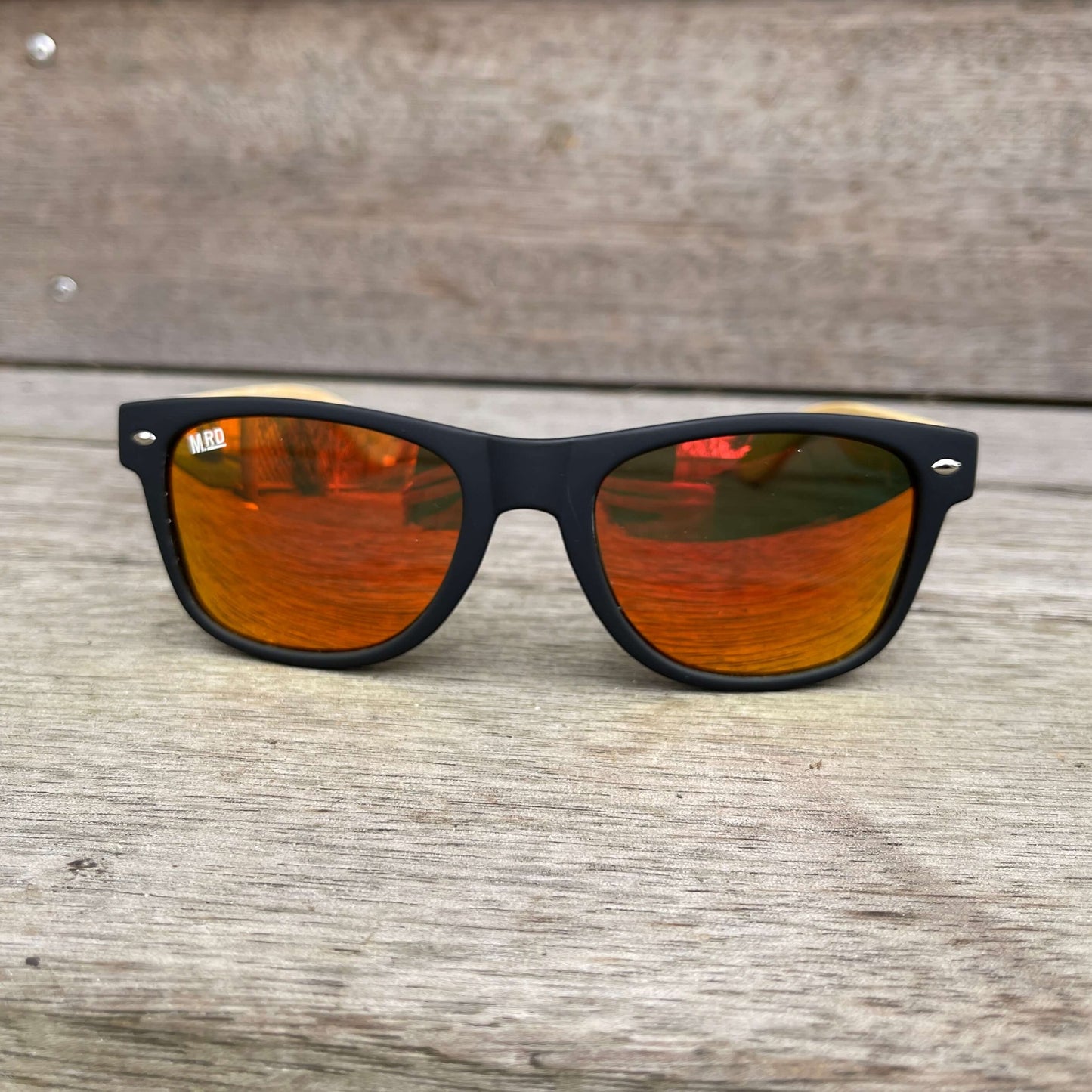 Sunglasses with wooden arms, black frames and reflective lenses.