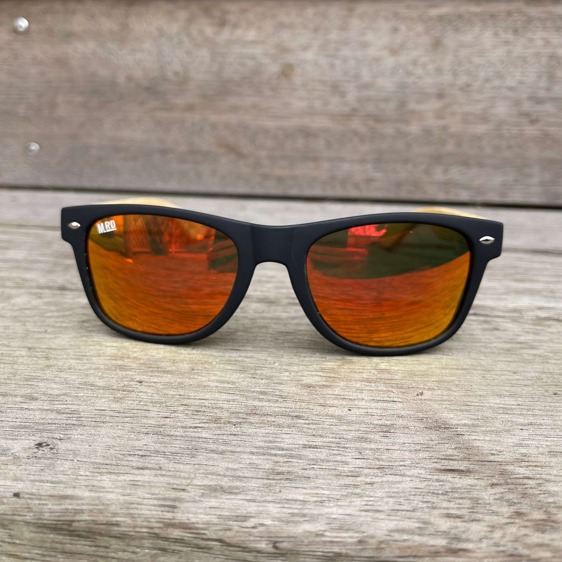Sunglasses with wooden arms, black frames and reflective lenses.