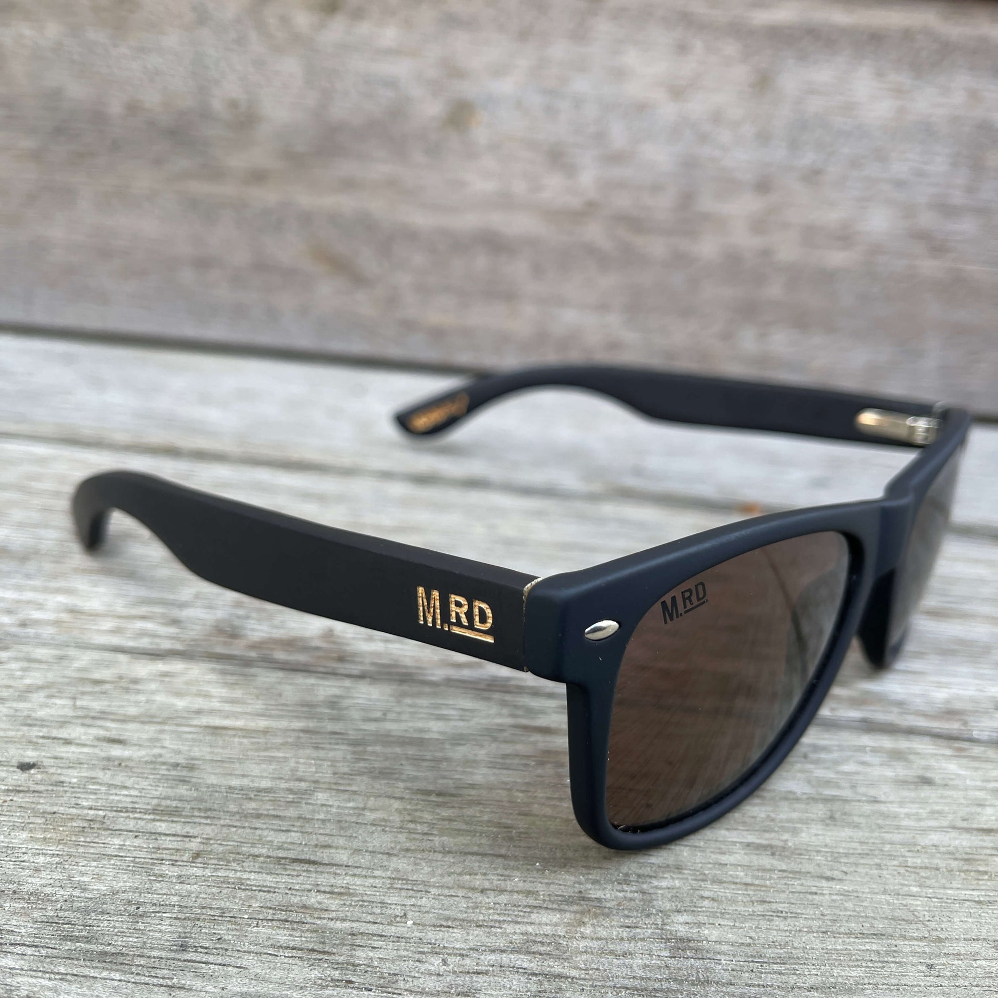 Sunglasses with dark wooden arms, black frames and dark lenses.