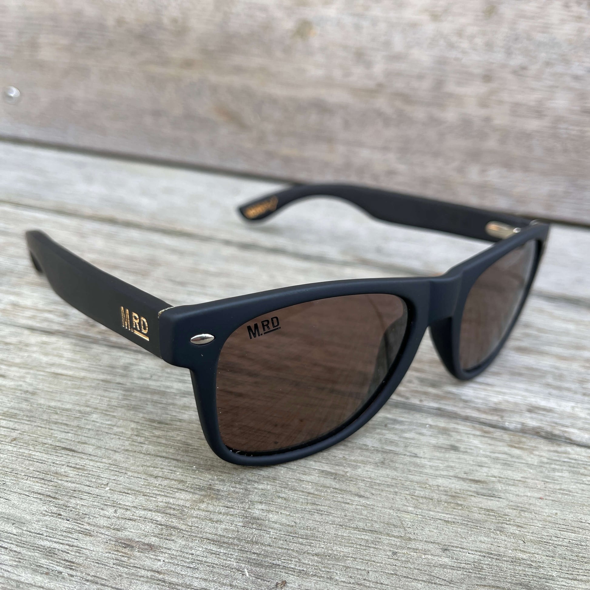 Sunglasses with dark wooden arms, black frames and dark lenses.